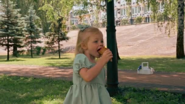 ポートレート 緑の夏のドレスの小さなかわいい女の子 おいしいアイスクリームを食べる 子供とアイスクリーム市公園夏の家族のライフスタイル 子供時代 — ストック動画