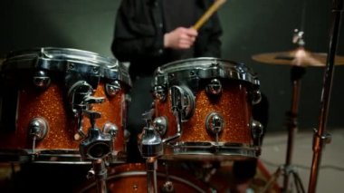 Davulcu profesyonel bir müzisyenin prova stüdyosunda davul çalar. Bir şarkı enstrümanın yakın çekimini geçer.