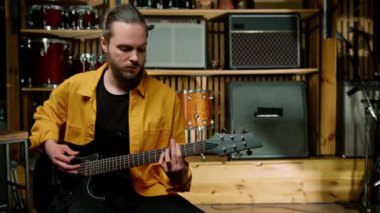 Stüdyoda elektro gitarlı genç bir rock sanatçısının portresi kendi müzik aleti davullarını çalıyor.