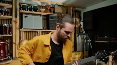Stüdyoda elektro gitarlı genç bir rock sanatçısının portresi kendi müzik aleti davullarını çalıyor.