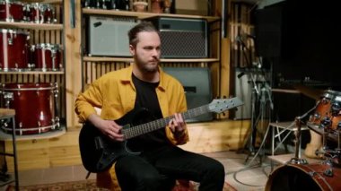 Stüdyoda elektro gitarlı genç bir rock sanatçısının portresi kendi müzik aleti davullarını çalıyor.