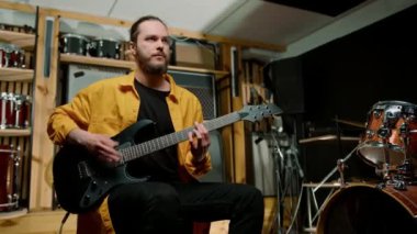 Stüdyoda elektro gitarlı genç bir rock sanatçısının portresi kendi müzik aleti davullarını çalıyor.