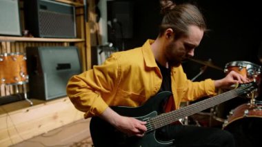 Stüdyoda elektro gitarlı genç bir rock sanatçısının portresi kendi müzik aleti davullarını çalıyor.