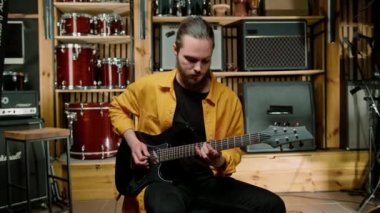 Stüdyoda elektro gitarlı genç bir rock sanatçısının portresi kendi müzik aleti davullarını çalıyor.