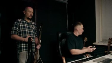 Elektro gitar kayıt stüdyosu ile rock sanatçısı ses mühendisiyle kendi şarkısını çalıyor.