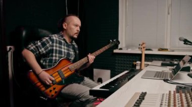 Stüdyoda elektro gitarlı bir rock müzisyeni kendi müzik enstrümanı tellerini çalıyor.