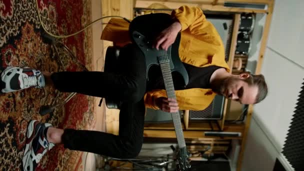 年轻摇滚歌手的肖像与电吉他在录音室播放自己的曲目乐器鼓背景垂直视频 — 图库视频影像