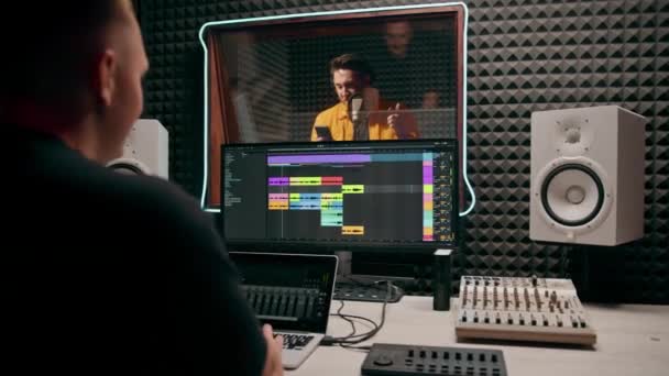 若いポップ ラップ アーティスト 感情的に新しい歌を記録する プロのレコーディング スタジオ サウンド エンジニア ディスプレイ上のトラックを見る — ストック動画