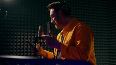 Genç pop rap sanatçısı, cam arkasında profesyonel kayıt stüdyosunda yeni bir şarkı kaydediyor.