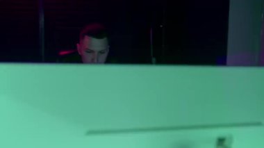 Profesyonel ses kayıt stüdyosu ses mühendisi ya da müzik yapımcısı uzaktan kumandada oturup, ekrandaki neon ışıkları karıştırıyor.