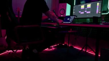 Profesyonel ses kayıt stüdyosu ses mühendisi ya da müzik yapımcısı uzaktan kumandada oturup, ekrandaki neon ışıkları karıştırıyor.