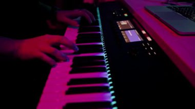 profesyonel kayıt stüdyosu ses mühendisi müzik yapımcısı sentezleyici tuşlarına basan müzisyen kırmızı neon ışığı