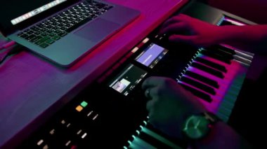 profesyonel kayıt stüdyosu ses mühendisi müzik yapımcısı sentezleyici tuşlarına basan müzisyen kırmızı neon ışığı
