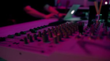 Profesyonel ses kayıt stüdyosu ses mühendisi ya da müzik yapımcısı uzaktan kumandada oturup, ekrandaki neon ışıkları karıştırıyor.