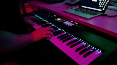 profesyonel kayıt stüdyosu ses mühendisi müzik yapımcısı sentezleyici tuşlarına basan müzisyen kırmızı neon ışığı