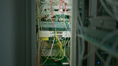 Bir sürü yama ağı kablosu veri merkezi internet depolama odasındaki bir sunucu rafındaki yama panelinden sıralanmış.