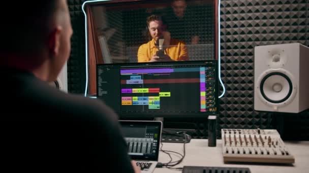 若いポップ ラップ アーティスト 感情的に新しい歌を記録する プロのレコーディング スタジオ サウンド エンジニア ディスプレイ上のトラックを見る — ストック動画