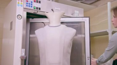Temizlik işçisi, çamaşır odasında çamaşır ütülemek ve endüstriyel otel konukseverliği için ceketini mankene giydirdi.