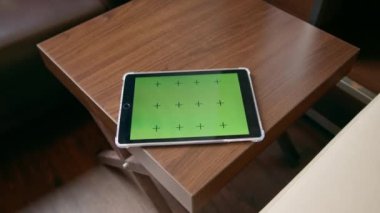 Masanın üzerinde yeşil ekranlı bir tablet var. Konsept teknoloji ve iletişim.