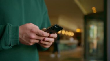 Otel resepsiyonundaki bir konuk elinde bir telefonla konukseverlik ve teknoloji konseptini bekleyen biriyle mesajlaşıyor.