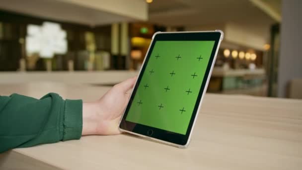 チェックインのおもてなしとテクノロジーコンセプトを手元に緑色のタブレットを手に持つホテルのフロントでゲスト — ストック動画