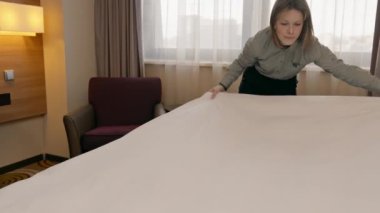 Otel temizlikçisi kızın portresi beyaz yatak temizliği konukseverlik konsepti yapar.