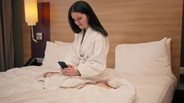 Lüks bir otel odasında beyaz önlüklü genç bir kız akıllı bir telefon tutuyor ve iş meselelerini geziden sonra çözüyor.