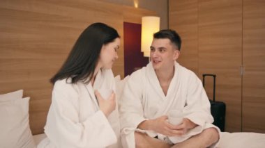 Genç çift balayında otel odasında kahvaltı yapıyor. Kahve içiyor, mutlu aşıklar seyahat ediyor.