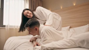 Balayında genç bir çiftin portresi otel odasında beyaz elbiseler içinde uzanmış mutlu aşıklar ile flört ediyor.