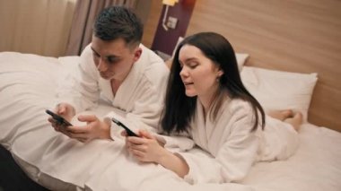 Lüks bir otel odasındaki genç çift akıllı telefonları ellerinde tutuyor. Birbirleriyle iletişim kurmuyorlar.
