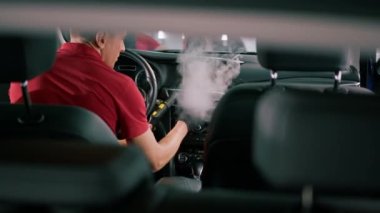 Bir oto yıkama işçisi lüks bir arabanın içini dikkatlice temizler fırça fırçası ve elektrikli süpürgeyle yakın plan temizlik yapar.