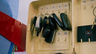 Erkek bir tamirci araba servisinin duvarına asılan bir arabayı tamir etmek ya da yıkamak için bir araba anahtarı alır.