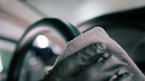 詳細な男性カーサービスの従業員は マイクロファイバー布のクローズアップで車内とステアリングホイールのドライクリーニングと洗浄を実行します — ストック動画
