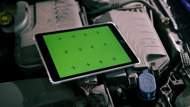 自動車サービスで高級車のエンジン上に緑色のスクリーンが開かれるタブレットのクローズアップ — ストック動画