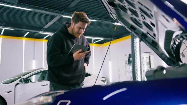 Mecánico Automóviles Masculino Con Una Tableta Sus Manos Encuentra Capucha — Vídeo de stock