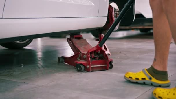 在汽车维修和干洗过程中 白色豪华轿车被吊起 车上装有红轮换档千斤顶 — 图库视频影像