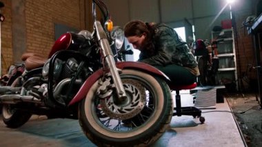 Yaratıcı otantik motosiklet atölyesi. Motorcu garajındaki sakallı, sakallı tamirci. Motosiklet, kabloları bıçakla temizliyor.