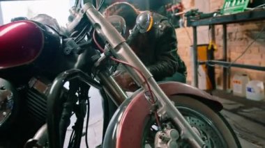 Yaratıcı otantik motosiklet atölyesi kızıl saçlı sakallı tamirci motorsikleti tamir ediyor.