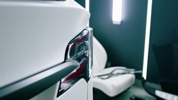 車のサービスで削除された車の座席の背景に対する豪華な白い車のテールライトとバンパーの詳細を閉じる — ストック動画