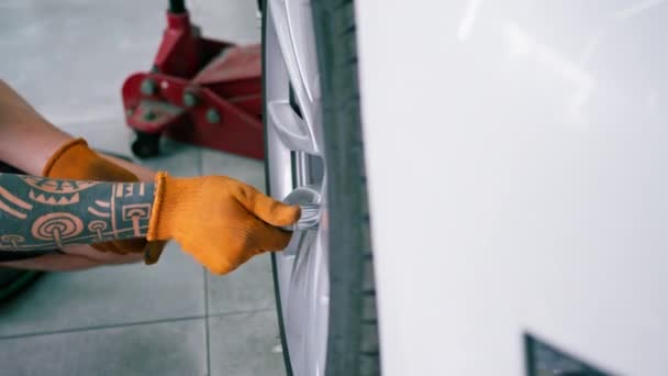 汽车修理工用汽球扳手在汽车维修站的特写镜头上更换豪华白色轿车上的车轮 — 图库视频影像
