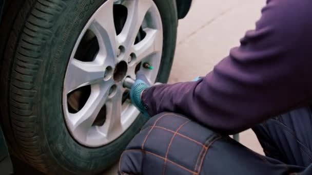 汽车修理工在街上的轮胎车间里用钻头把一辆黑色汽车的轮子换掉 详细说明汽车修理的情况 — 图库视频影像