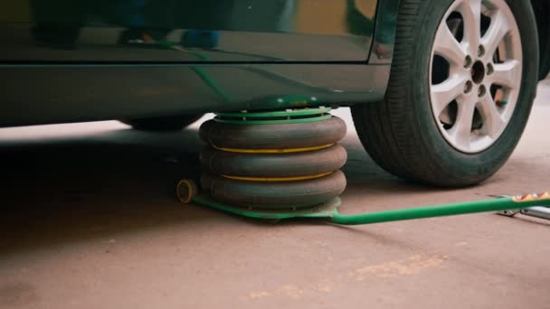 詳細とドライクリーニング中に自動車修理店で車輪を変更するために空気圧ジャックで持ち上げられている黒の高級車 — ストック動画