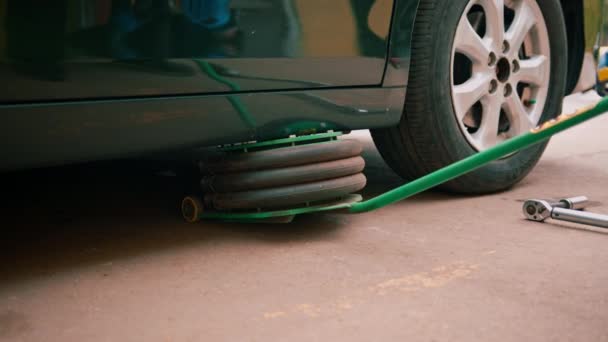 詳細とドライクリーニング中に自動車修理店で車輪を変更するために空気圧ジャックで持ち上げられている黒の高級車 — ストック動画