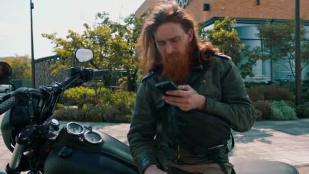 Portret Brutalny Zamyślony Rudowłosy Brodaty Motocyklista Siedzi Czarnym Motocyklu Telefonem — Wideo stockowe