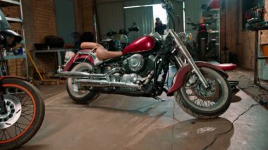 Yaratıcı otantik motosiklet atölyesi kızıl saçlı sakallı tamirci motorcu garajına girer işe başlamadan önce motosiklete bakar.
