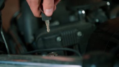 Yaratıcı otantik motosiklet atölyesi. Garaj tamircisi. Motoru çalıştırmak için anahtarı takıyor.