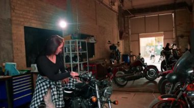 Otantik motosiklet atölyesi garajı portresi. Güzel, şirin, siyah motosikletli kız.