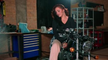 Otantik motosiklet atölyesi garajı portresi. Güzel, şirin, siyah motosikletli kız.