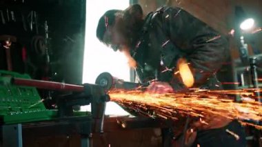 Yaratıcı otantik motosiklet atölyesi kızıl saçlı, sakallı, vahşi motosikletli, dairesel testere ile sıcak metalden kıvılcımlar uçuşuyor.