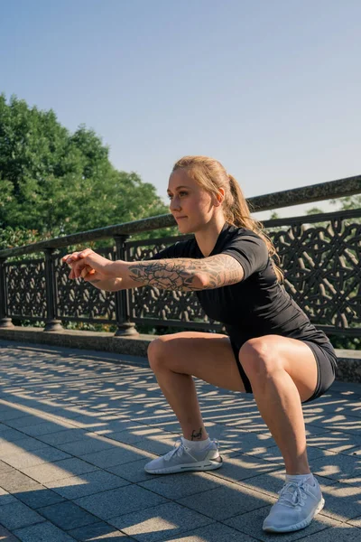 健康的年轻女运动员早上在公园进行户外运动时做热身运动 — 图库照片